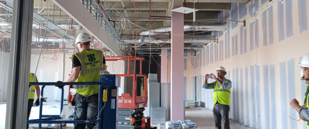Two people in high-vis working in temporary Redditch station
