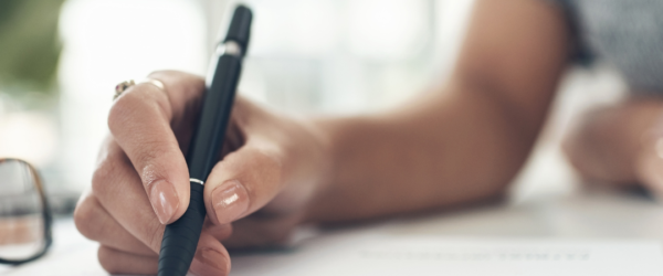 Person with pen writing on paper